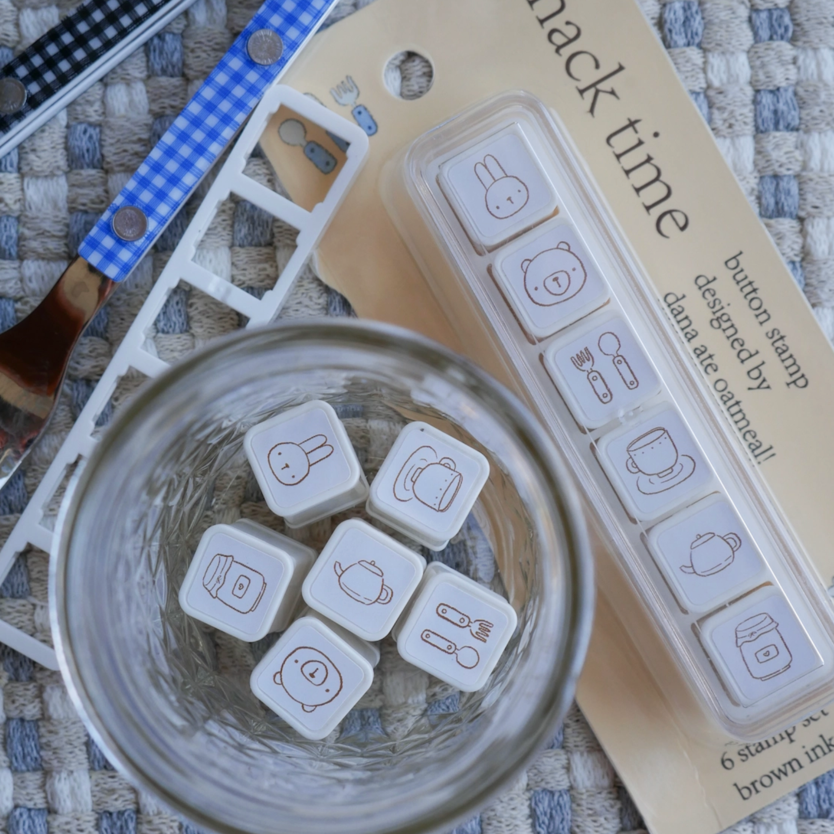 Set of snack time themed buttons in a glass with packaging on a textured surface